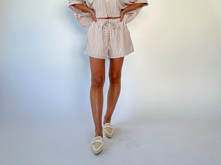 Person wearing a striped outfit with shorts on a plain background