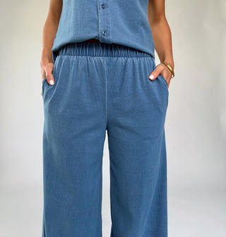 Person wearing blue corduroy pants and a matching top against a plain background