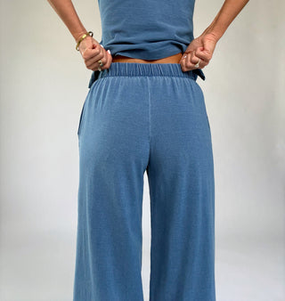 Person wearing blue pants and a blue top against a plain background