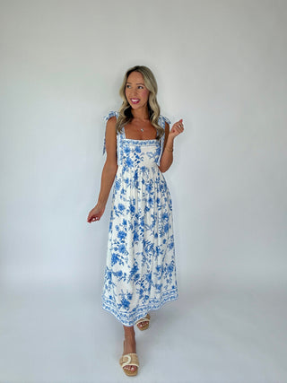 Woman wearing a blue floral dress against a white background
