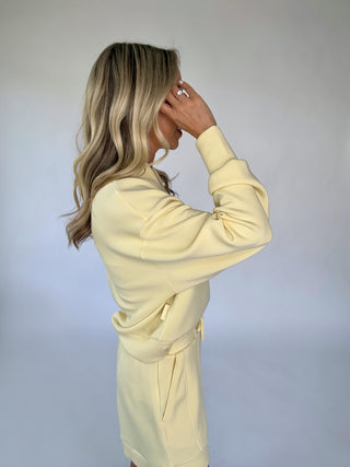 Woman wearing a light yellow outfit against a plain background