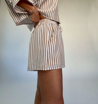 Person wearing a brown and white striped outfit against a plain background