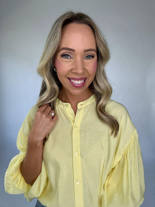 Woman wearing a yellow blouse against a plain background