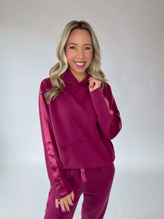 Woman wearing a wine berry tracksuit against a plain background