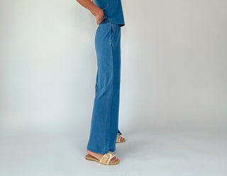 Person wearing blue pants and sandals on a white background