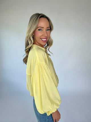 Woman wearing a yellow blouse against a plain background