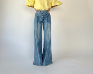 Person wearing a yellow shirt and blue jeans on a plain background