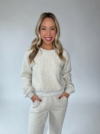 Woman wearing a white ribbed knit outfit against a plain background
