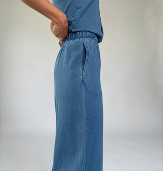 Person wearing blue pants and a matching top against a plain background