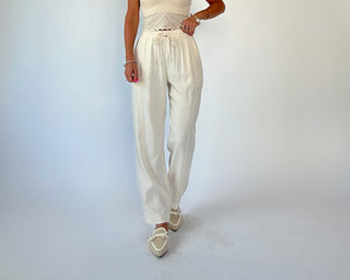 Person wearing a white outfit with wide-leg pants on a light gray background