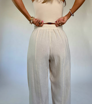 Person wearing a white top and beige pants against a plain background