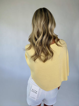 Person wearing a yellow top and white shorts with a plain background