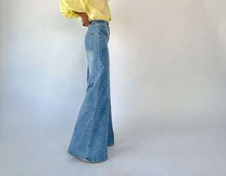 Person wearing a yellow shirt and blue flared jeans on a white background