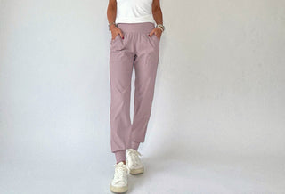 Person wearing light purple jogger pants and white sneakers on a plain background