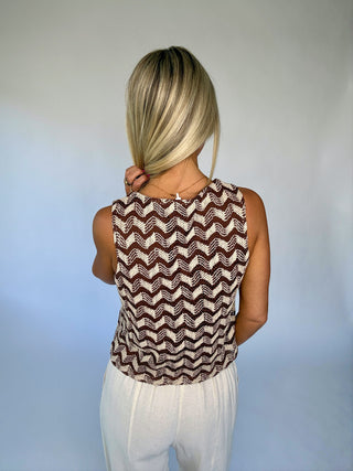 Person wearing a sleeveless top with a zigzag pattern against a plain background