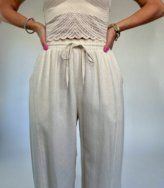 Beige jumpsuit with lace top and wide-leg pants on a plain background