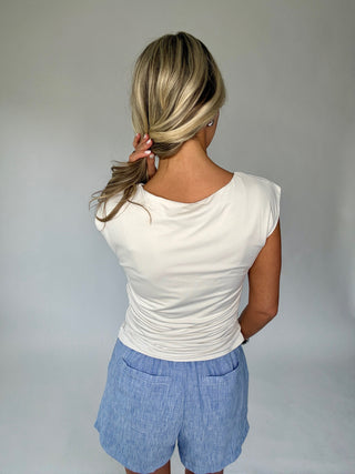 Person wearing a white top and blue shorts against a plain background