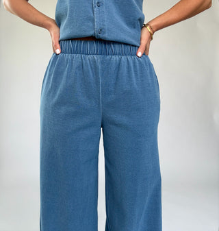 Person wearing blue corduroy pants against a plain background