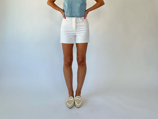 Person wearing white shorts and a denim top against a plain background