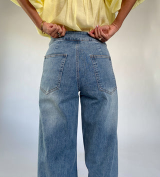 Person wearing a yellow shirt and blue jeans against a plain background