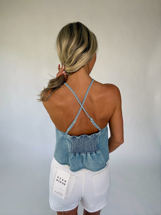 Woman wearing a denim top and white shorts against a plain background