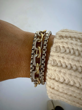 Close-up of a wrist wearing a gold and silver chain bracelet with a blurred background.