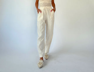 Person wearing a white outfit with high-waisted pants on a light gray background