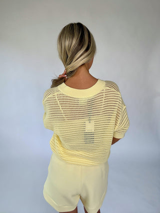 Person wearing a yellow mesh top and shorts against a plain background