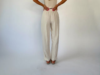Person wearing a beige top and wide-leg pants on a white background