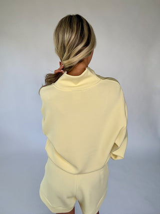 Person wearing a light yellow outfit against a plain background