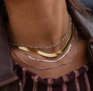 Close-up of a person wearing multiple necklaces with a blurred background