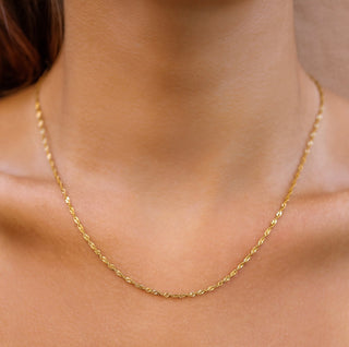 Gold necklace on a person's neck with a neutral background