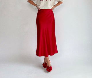 Person wearing a red skirt and white top on a plain background