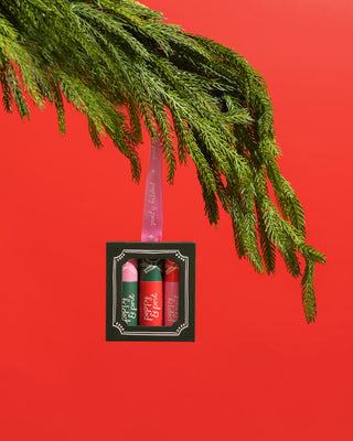 Set of lip balms in a black box with a green leafy branch on a red background