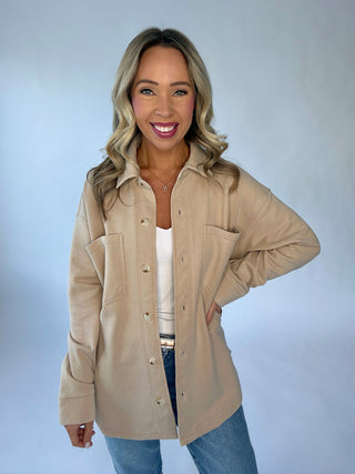 Woman wearing a beige jacket with a plain background