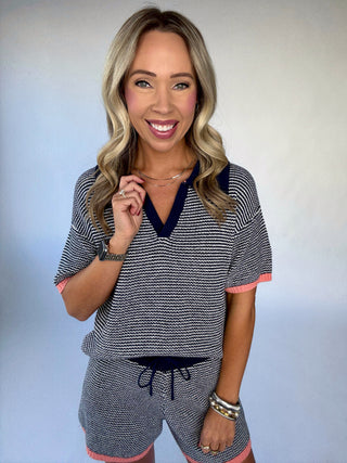 Woman wearing a black and white striped outfit with pink accents against a light blue background