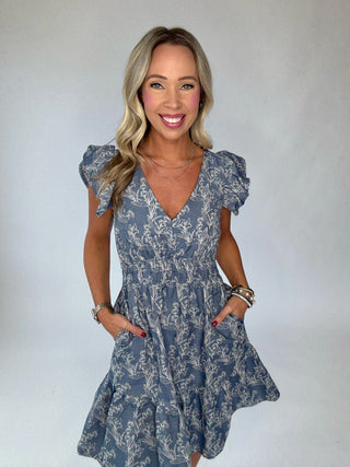Woman wearing a blue floral dress against a white background