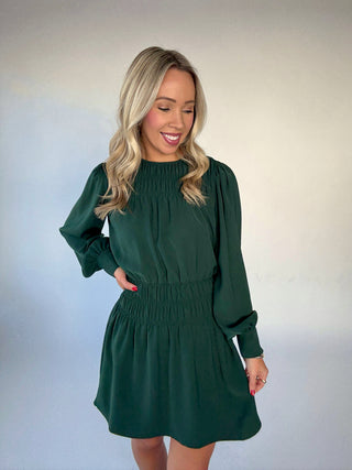 Woman wearing a green Holly dress against a plain background