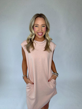 Woman wearing a light pink dress against a plain background