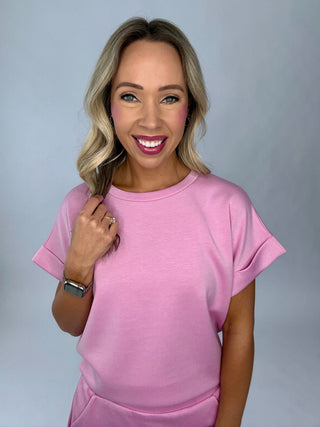 Woman wearing a pink outfit against a plain background